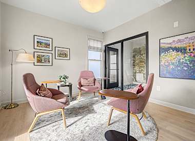 A living room with a grey rug and pink chairs.