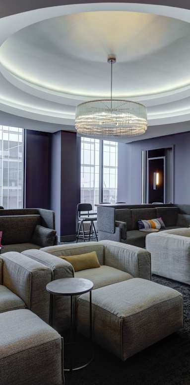 A modern living room with a circular light fixture and a grey couch.