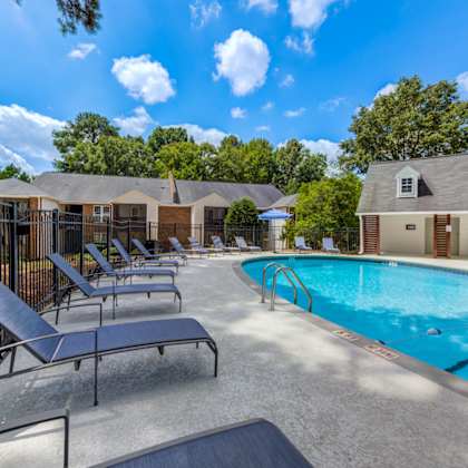 a pool area with sun loungers and a building in the background.