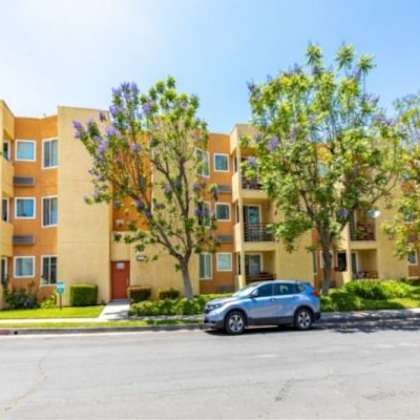 a sunny day at a residential building with cars parked in front.