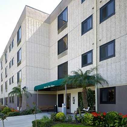 a large building with a green awning and a small garden in front.