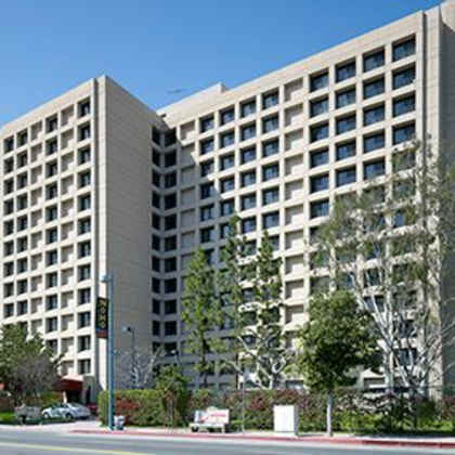 a large tan building with many windows sits on a street corner.
