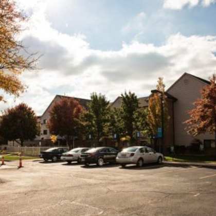 a parking lot with cars and trees in front of a building.