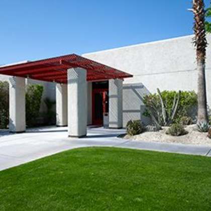 a white building with a red roof and pillars.