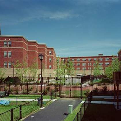 a long brick building with a black fence in front.