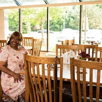 a woman in a floral dress sits in a restaurant.