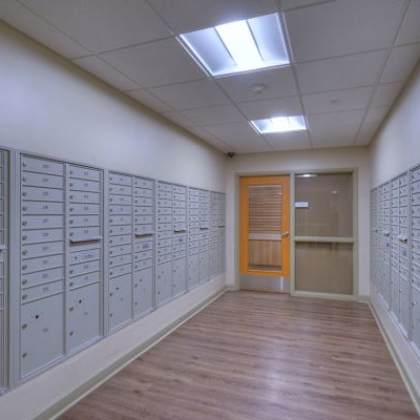 a hallway with a row of mailboxes on either side and a wooden floor.