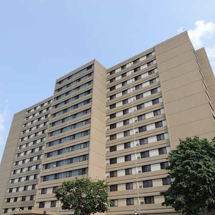 a tall building with many windows and trees in front.