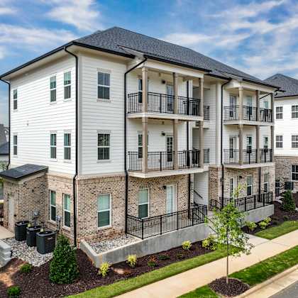 a row of modern apartment buildings with balconies and landscaped front yards.