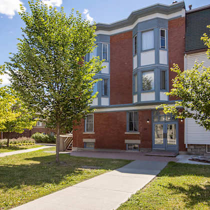 a red brick building with a green tree in front.