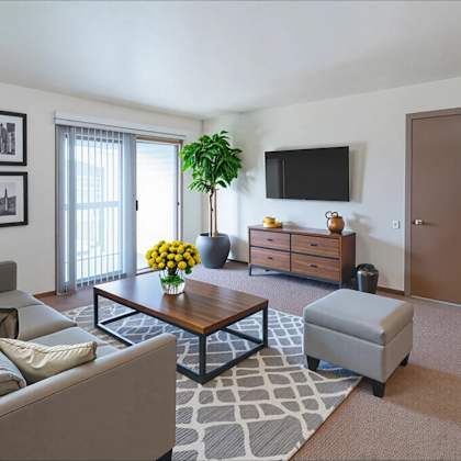 a living room with a grey couch, a coffee table, a plant, a tv, and a brown door.