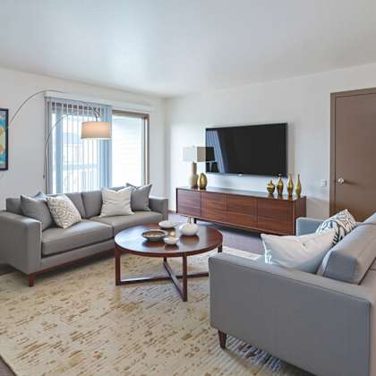 a living room with a grey couch, a coffee table, and a flat screen tv.