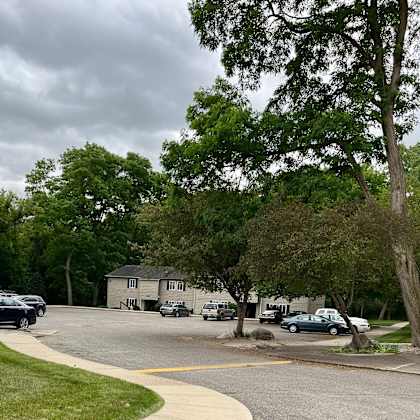 a parking lot with trees and cars in front of a house