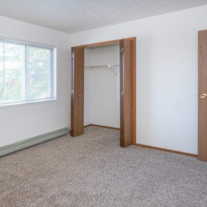 an empty bedroom with a closet and a window