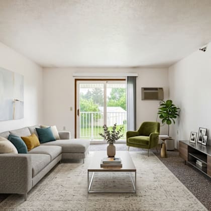 a living room with a grey couch, a green armchair, a coffee table, and a large window.