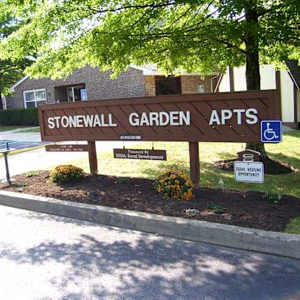 a brown sign that says stonewall garden apts.