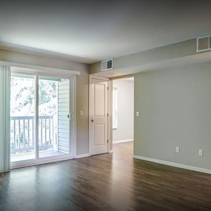 an empty living room with a door to a balcony