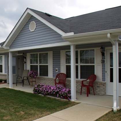 a blue house with rocking chairs on a porch