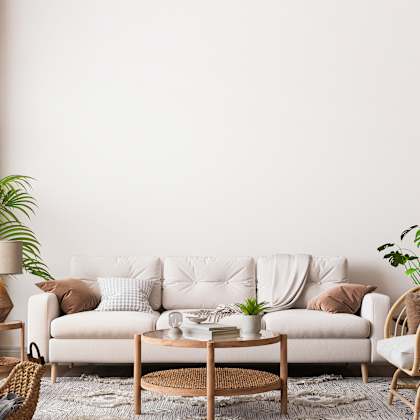 a living room with a white sofa, a wooden coffee table, and a wicker chair.