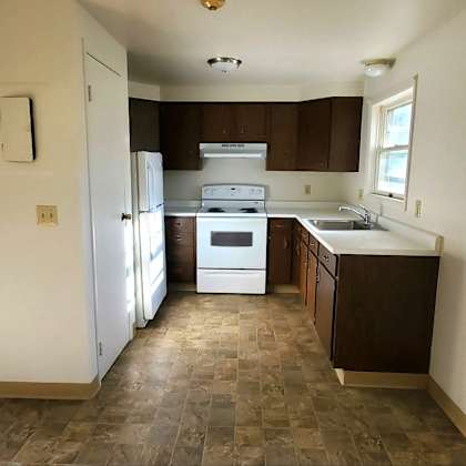 an empty kitchen with white appliances and a window