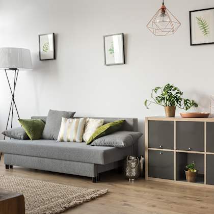 a living room with a grey couch and a wooden cabinet.