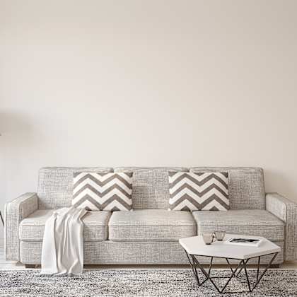a grey couch with a white cushion and a white table in front of it.