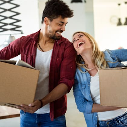 a man and a woman laughing while holding boxes