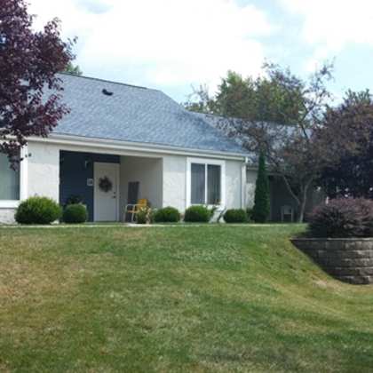 a white house with a lawn and a brick retaining wall
