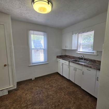 a kitchen with brown flooring and white cabinets.