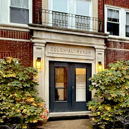 the colonial manor building has a black door and windows.