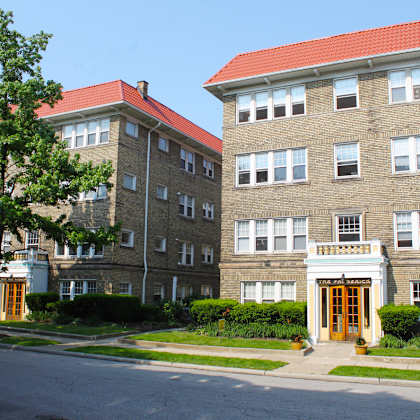 a view of two apartment buildings on the side of a street