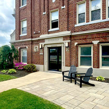 two black chairs are on a patio in front of a brick building.