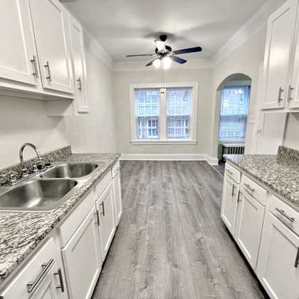 a kitchen with white cabinets and a marble countertop at heights collection apartments, ohio 44106