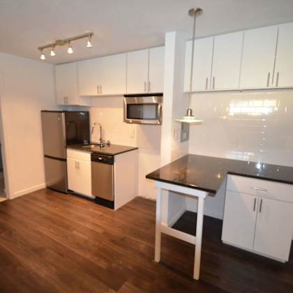 a kitchen with white cabinets and a black counter top.