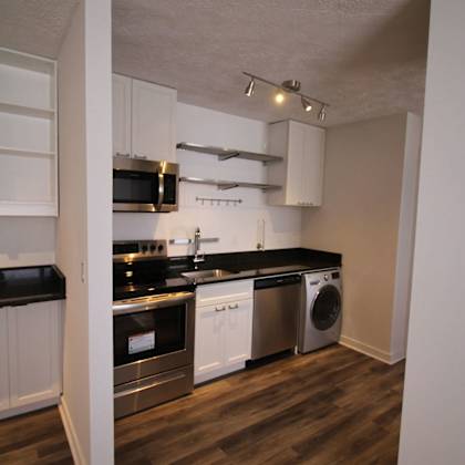 a kitchen with white cabinets and black countertops.