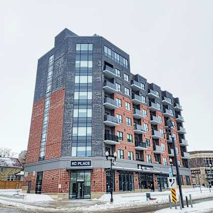 a tall building with a red brick base and a black top with the words kc place on it.