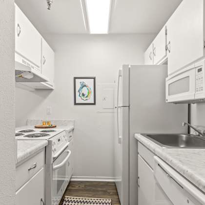 a small kitchen with white appliances and cabinets.