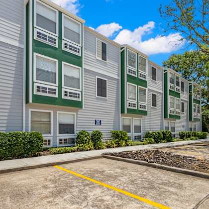 apartment building with a parking lot in front.