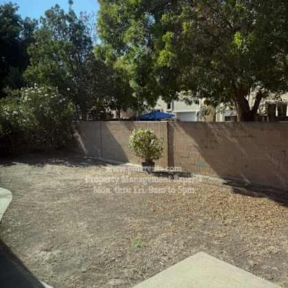 a backyard with a concrete patio and a wall.