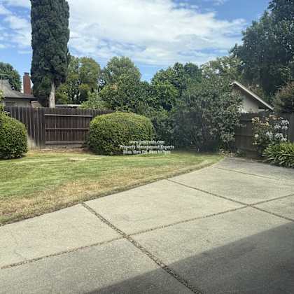 a backyard with a concrete patio and a wooden fence.