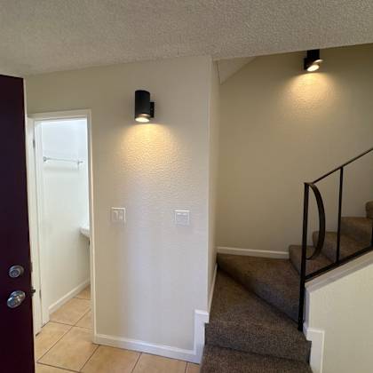 a hallway with a staircase and a black door.