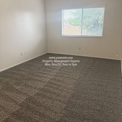a room with a carpeted floor and a window with blinds.