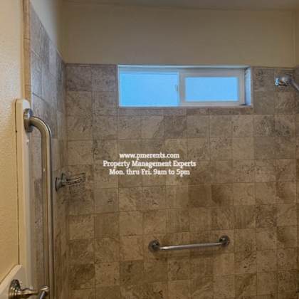 a tiled shower with a window above it.