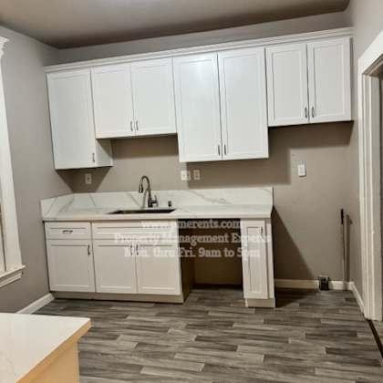 a kitchen with white cabinets and a marble countertop.