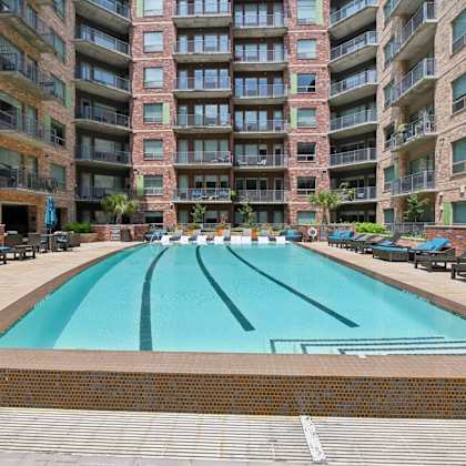 a large swimming pool in front of a multi-story apartment building.