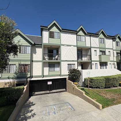 a green and white apartment building with a black gate in front.