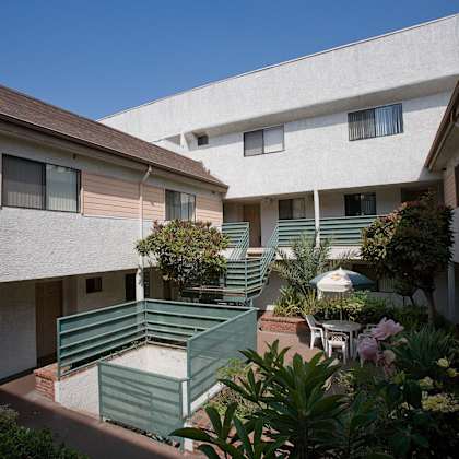 a courtyard with a green bench and a white umbrella.