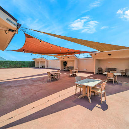 a patio with a table and chairs under a shade sail.