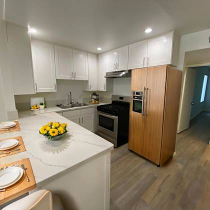 a kitchen with a table set for four with a vase of flowers on it.