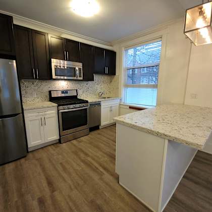 a kitchen with a refrigerator, microwave, oven, and cabinets.